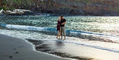 vacaciones Pareja caminando en playa juntos en amor participación alrededor cada otro. contento interracial joven pareja, asiático mujer y caucásico hombre. foto