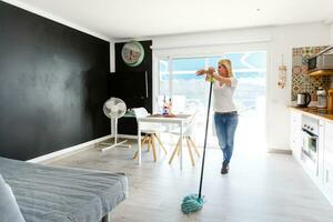 Cleaning concept. Young woman washing floor on the kitchen photo