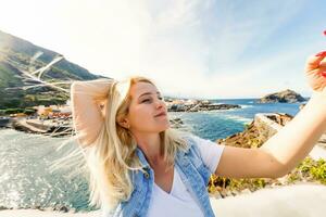 Young girl smiling and speaking consulting and giving instruction with voice recognition. Woman with audio recording in smart phone in the seaside in Garachico, Tenerife photo