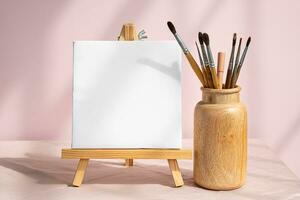 Blank white canvas and vase with paintbrushes for art. Artistic layout. photo