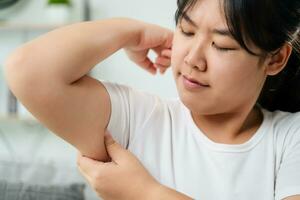 Close up of Chubby woman pinching upper arm fat. weight loss concept. photo