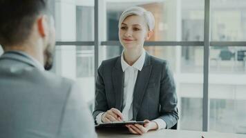 HR businesswoman having job interview with young man in suit and watching his resume application in modern office indoors photo