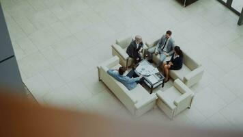 Top view of group of business people colleagues discussing financial charts sitting on couchs in lobby at modern business center indoors photo