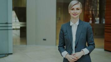 Portrait of successful blonde businesswoman smiling and looking into camera in modern office indoors photo