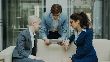 Cheerful businessman talking and discussing about financial report with business female colleagues sitting on sofa in meeting room indoors photo