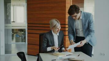 Two business colleagues discussing reports in modern office indoors. Businesswoman sitting at the table talking his male partner photo