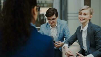 Businesswoman talking and duscussing future deal with business partners sitting on couch in modern office center indoors photo