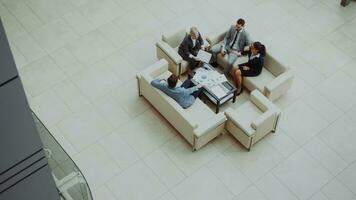 Top view of group of business people colleagues discussing financial charts sitting on couchs in lobby at modern business center indoors photo