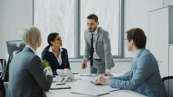 Businesswoman discussing reports with male and female colleagues sitting at the table in modern office indoors photo