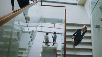 Top view of two businessmen meet at staircase in modern office center indoors and talking while female colleagues walking stairs photo