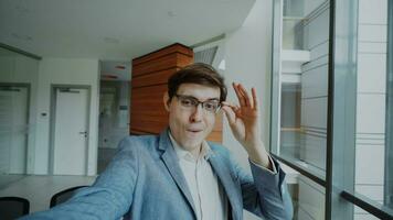 pov de joven alegre empresario en lentes tomando un selfie foto y tener divertido en moderno oficina adentro