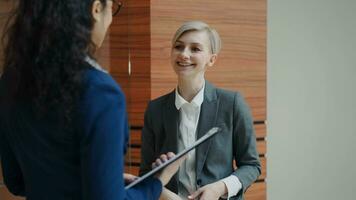 Two businesswomen colleagues talking in modern office indoors photo