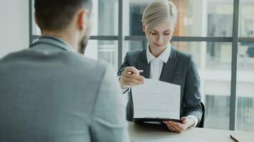 HR businesswoman having job interview with young man in suit and watching his resume application in modern office indoors photo