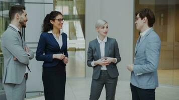 Businesswoman talking to her colleagues while standing in office lobby indoors. Group of business people discussing future deal photo