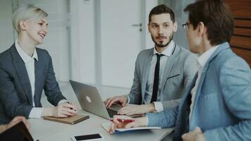 Businessman discussing future business project with male and female colleagues sitting at the table in modern office indoors photo