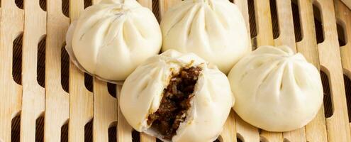 chino alimento, baozi es un tradicional delicadeza en porcelana, un pan comida fotografía entonces tentador, delicioso baozi, chino al vapor carne bollo es Listo a comer en servicio plato y buque de vapor foto