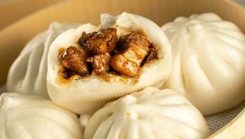 chino alimento, baozi es un tradicional delicadeza en porcelana, un pan comida fotografía entonces tentador, delicioso baozi, chino al vapor carne bollo es Listo a comer en servicio plato y buque de vapor foto