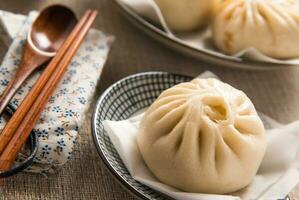 Chinese food, Baozi is a traditional delicacy in China, Bread Food Photography So Tempting, Delicious baozi, Chinese steamed meat bun is ready to eat on serving plate and steamer photo