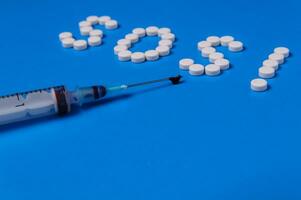 Syringe and SOS from pills on a blue background. Prevention of viral diseases. photo