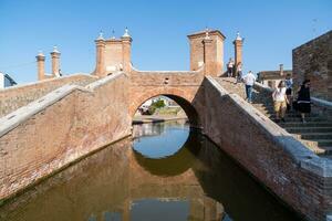 Comacchio ,Italy-June 2, 2023-people stroll in Comacchio in front off the  famous three bridges during a sunny day photo