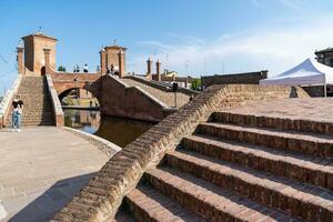Comacchio ,Italy-June 2, 2023-people stroll in Comacchio in front off the  famous three bridges during a sunny day photo