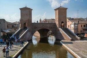 Comacchio ,Italy-June 2, 2023-people stroll in Comacchio in front off the  famous three bridges during a sunny day photo