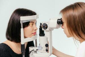 Woman having vision test on an ophthalmology diagnostic vision testing equipment. Doctor doing eye test with non contact tonometer, checking vision at optical clinic photo