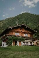 Wood chalet over Swiss Alps. Traditional Austrian view of the village, house, mountains and sky, summer background. Typical wooden alpine house decorated with flowers on green meadow photo