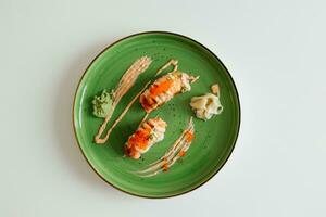 Sushi nigiri with a grilled salmon and caviar. Sushi rolls on green plate with wasabi and ginger. Top view with copy space. Traditional japanese dish. photo