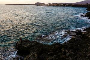 marina con atlántico Oceano y el cielo a crepúsculo, piedras en el playa y pescadores en el muelle. largo exposición con borroso mar agua foto