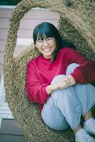 asian teenager toothy smiling with happiness face ,relaxing on bamboo cradle. photo