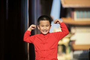 portrait asian boy wearing chinese red suit standing outdoor photo