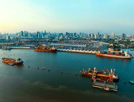 aerial view of commercial ship and container dock  in chaopraya river with urban skyline in bangkok thailand capital photo