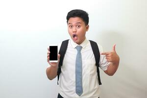 indonesio mayor alto colegio estudiante vistiendo blanco camisa uniforme con gris Corbata demostración y presentación blanco pantalla móvil teléfono. aislado imagen en blanco antecedentes foto