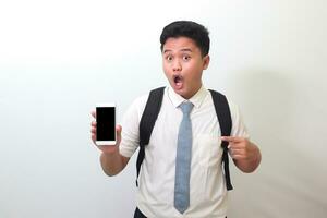 Indonesian senior high school student wearing white shirt uniform with gray tie showing and presenting blank screen mobile phone. Isolated image on white background photo