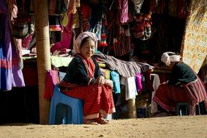 Chiangmai Tailandia - enero 10, 2016 no identificado tailandés del Norte colina tribu sentado a tradicion mano hecho colina tribu ropa en doi ang khang uno de más popular invierno de viaje destino foto