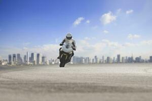 man riding big motorcycle on asphalt highway against urban skyline background photo