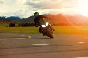 hombre montando deporte motocicleta propensión en agudo curva con de viaje escena antecedentes foto