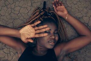 Beautiful African female on dry cracked ground in the desert photo