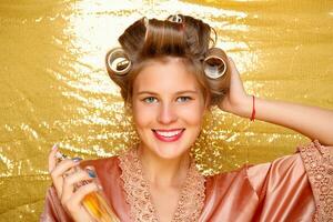 Beautiful girl in hair curlers isolated on gold photo