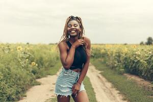 africano americano niña en un campo de amarillo flores a puesta de sol foto