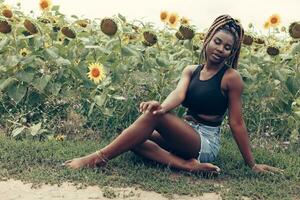 africano americano niña en un campo de amarillo flores a puesta de sol foto
