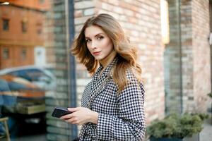 woman in trench coat walking and drinking coffee from paper cup photo