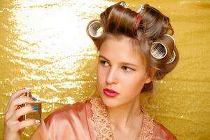 Beautiful girl in hair curlers isolated on gold photo