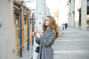 Attractive girl in a coat in the street in a city, sun is shining photo