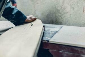 Young artisan man sandering the deck with the hand photo