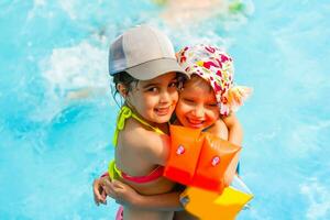 dos pequeño muchachas jugando en el piscina foto