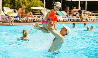 Father playing with his daughter in swimming pool photo