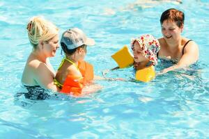 two women and their children in the pool photo