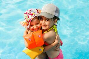 dos pequeño muchachas jugando en el piscina foto